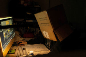 person wearing a box on their head sitting at a desk