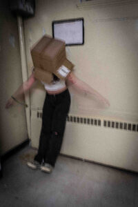 person with a box on their head leaning back with arms wide open. They are blurry